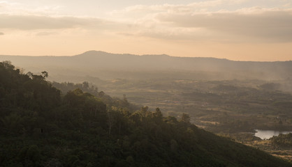 a landscape view of village in the middle of green mountains during sunset time.