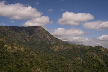 Fototapeta na wymiar range of green mountain under cloudy blue sky