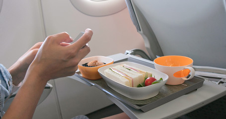 Woman taking photo on her flight meal on plane