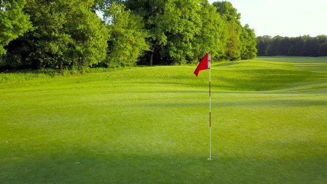 Low height drone video of a golf hole flag surrounded by beautiful nature