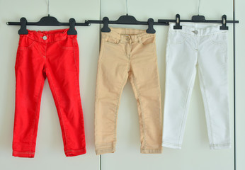 A row of baby trousers on a hanger