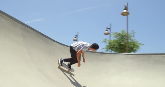 Man skateboarding pumping in bowl on sunny day