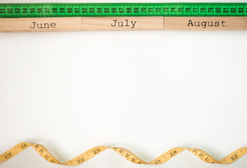 Three summer month - June, July and August - on wooden blocks with centimeter tape isolated on white. Summer calendar concept