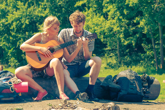 Young couple camping playing guitar outdoor