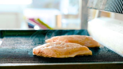 A steak of fresh fish is fried on a hot grill with aroma and smoke
