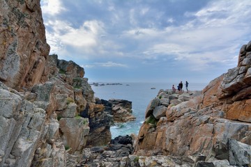 Fototapeta na wymiar Des gens qui discutent sur les grands rochers du site du gouffre à Plougrescant en Bretagne