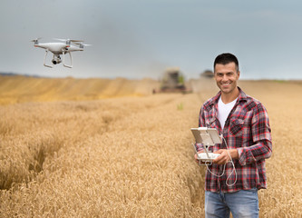Farmer with drone in front of combine harvester - obrazy, fototapety, plakaty