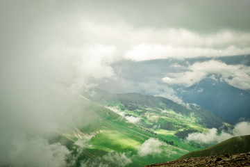 mountain valley and mountain peaks with the remains of snow on the slopes closed by low dense clouds landscape illustration background