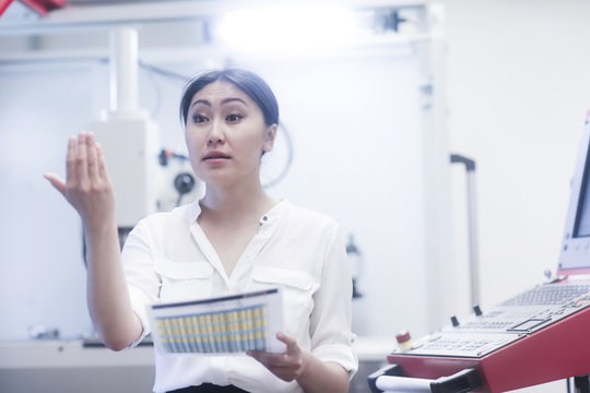 Female engineer holding a data sheet gesturing with her hand