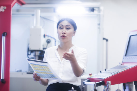 Female engineer holding a data sheet gesturing with her hand