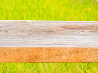 Wooden table or chair with blurry rice paddy or field background.