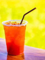 Closeup of lemon tea on wooden table with blurry yellow background.