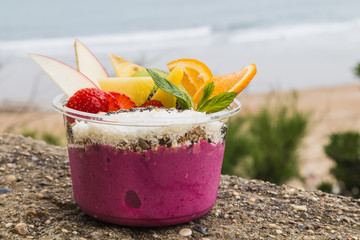 Takeaway acai bowl with fresh fruit and mint leaves
