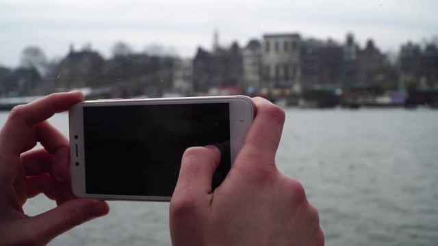 girl sail on a boat through the canals in Amsterdam and takes pictures on the phone