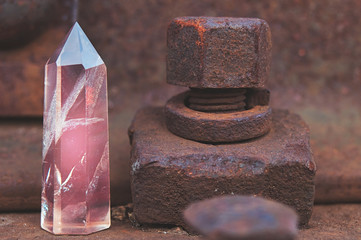 Large transparent mystical faceted crystal of colored pink amethyst, chalcedony on a rails on industrial background close-up. Wonderful mineral of the royal size for the designer