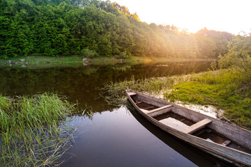 old wooden boat shore of river surrounded by forest at sunny summer day