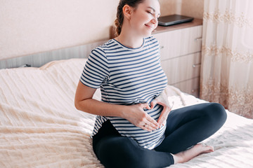Obraz premium Pregnant Woman Belly. Pregnancy Concept. In living room. Pregnant tummy close up