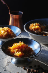 Dish for dessert with coffee ice, a bowl and grains on the table side view. Sicilian granite