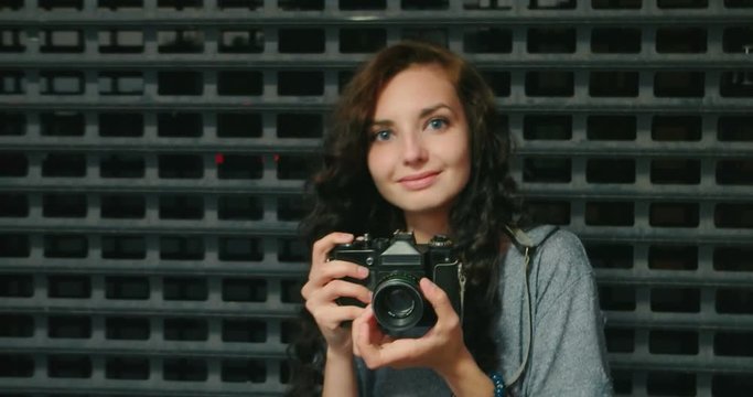 Happy Teen Girl Taking Photo By Vintage Film Camera In Front Of Metal Fence