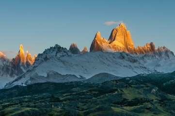 Fototapeta na wymiar The Fitz Roy mountain range glowing in the golden colour of sunrise on a crisp clear morning, El Chalten, Argentina. Ice and strong wind make Fitz Roy the hardest peak to climb on the planet.
