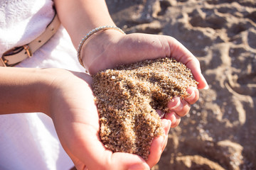 Mellow heart shaping female hands above beach