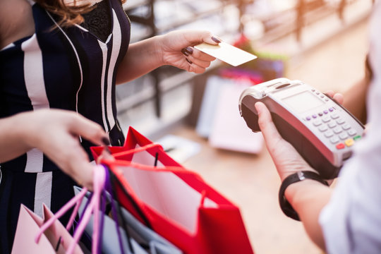 A Woman Uses A Credit Card To Pay For Goods With A Cashier. Shopping Concept.