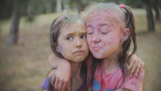 Two little girls smeared with colored powder Holi sprinkle water