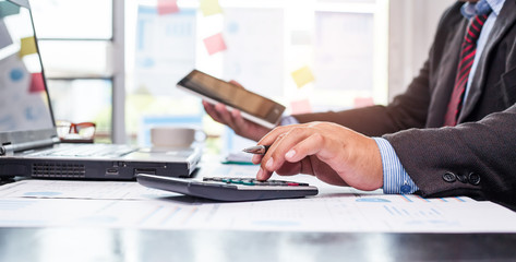A businessman analyzing investment charts with using calculator for calculate of finance at workplace. Business concept.