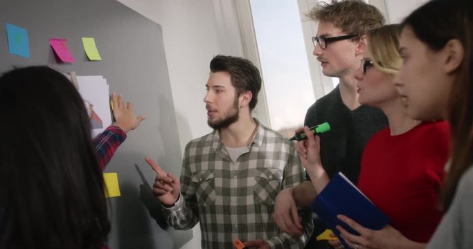 A group of concentrated Students working on a pinboard with notes to describe the meaning of statistics homework