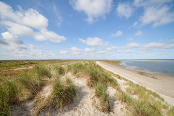 Fototapeta na wymiar Dunes with beach and blue sky with clouds