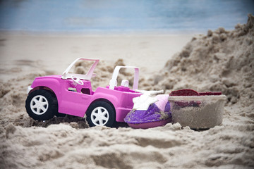 Toy car on the beach with the sea in the background