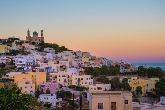 Panoramic view of Ermoupoli city of Syros Island in Cyclades, Greece.  View of the colorful houses and the Orthodox Anastaseos church on sunset 