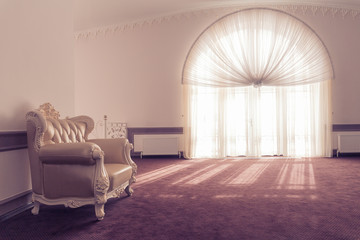 Armchair in a room with a large window, carpet and sunlight. Space where you can mount a person.