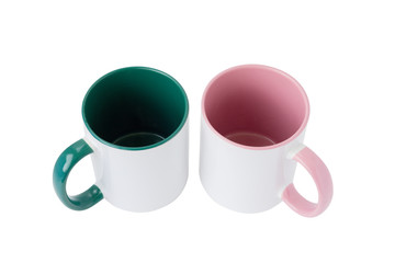 Two white mugs, with a green and pink handle on a light background. Isolated.