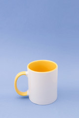 White mug with a yellow handle on a background of a blue background.