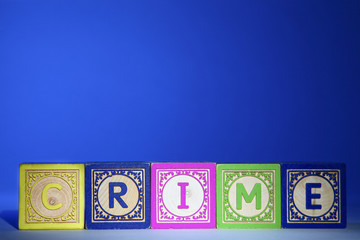 Wooden letter blocks on a blue background spelling out the word crime