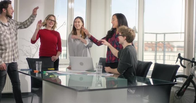 Multiethnic group of business people making a group high five in their conference room