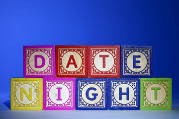 Wooden letter blocks on a blue background spelling out the words date night