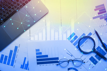 Magnifying glass and documents with analytics data lying on table,selective focus