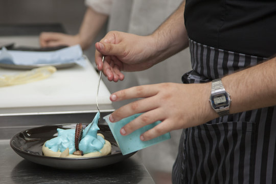 The cook prepares an octopus dish with turquoise sauce