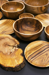 Wooden utensils for the kitchen, bowls, plates on a black background. The concept of natural dishes, a healthy lifestyle. Texture of wood. Wooden eco-ware