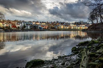 Obraz premium A view of Trondheim reflected in the river. Sunset before the storm. Norway