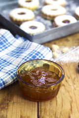 homemade apricot jam in glass bowl with algerian linzer cookies on silver plate