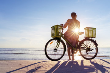 Obraz premium Woman spending day off on a beach, bicycle and girl silhouette in sunlight