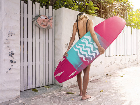 Woman with pink surf board standing on a beach surf house space