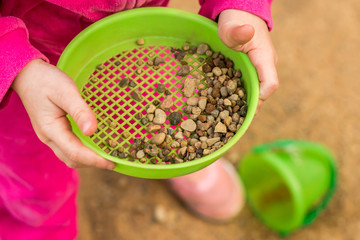 The child is playing in the sandbox. Children's hands.