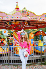 Bright summer concept. A cheerful blonde girl in pink jacket and stylish sunglasses is having fun...