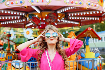 Bright summer concept. A cheerful blonde girl in pink jacket and stylish sunglasses is having fun...