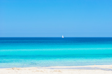 Fototapeta na wymiar Sommer Hintergrund Sand Strand mit Blau Türkis Meer Wasser und Segelboot am Horizont