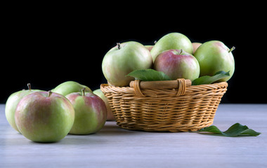 fresh apples in a basket on a wooden table on a black background